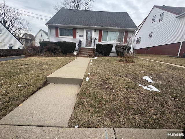 view of front of house with a front lawn and roof with shingles