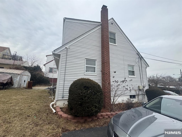 view of property exterior with a chimney, a storage unit, and an outdoor structure