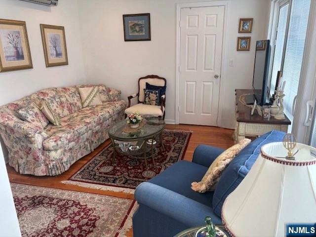 living room featuring a wall unit AC and wood finished floors