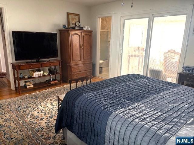 bedroom with ensuite bath and wood finished floors