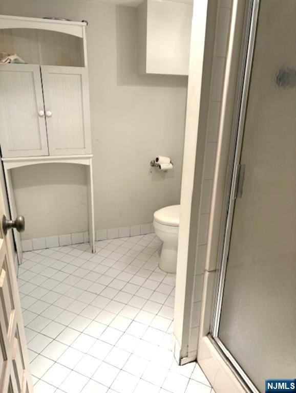 full bath with toilet, a shower stall, baseboards, and tile patterned flooring