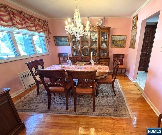 dining space featuring a chandelier, baseboards, light wood-style flooring, and crown molding