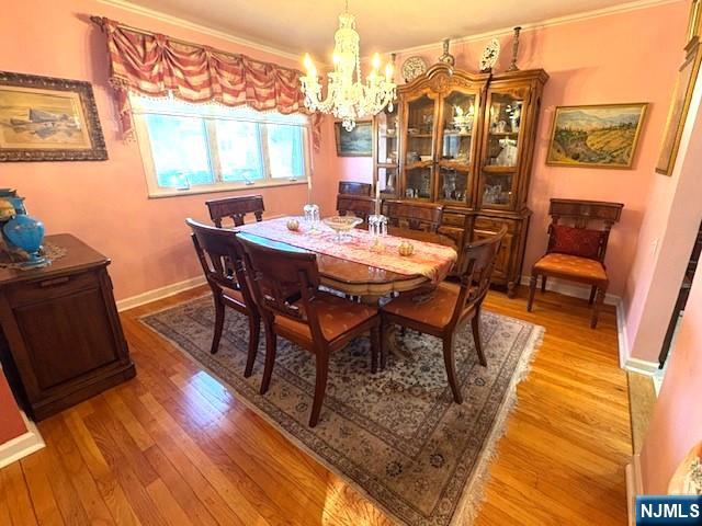 dining area with a chandelier, light wood-style flooring, and baseboards