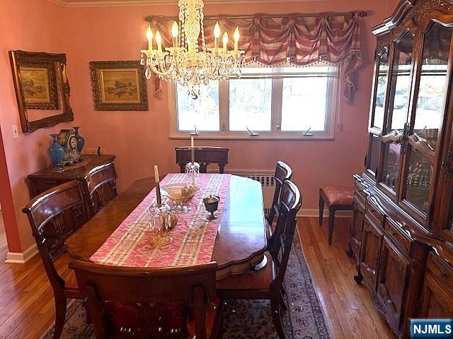 dining space featuring baseboards, wood finished floors, and a notable chandelier