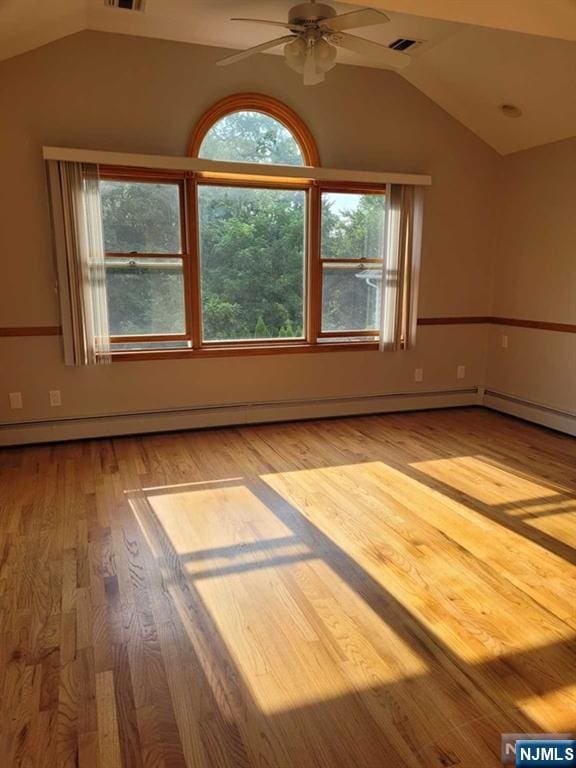 spare room featuring light wood-style floors, visible vents, vaulted ceiling, and a ceiling fan