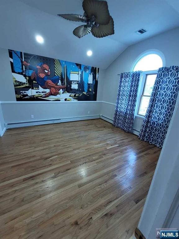 unfurnished room featuring ceiling fan, wood finished floors, visible vents, and lofted ceiling