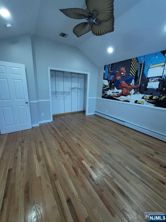 interior space featuring vaulted ceiling, wood finished floors, visible vents, and baseboards