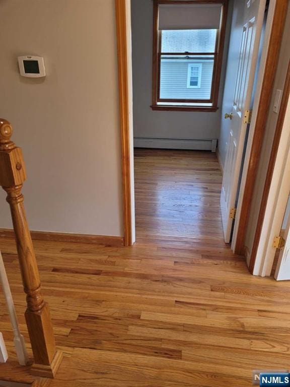 hall with baseboard heating and light wood-style flooring