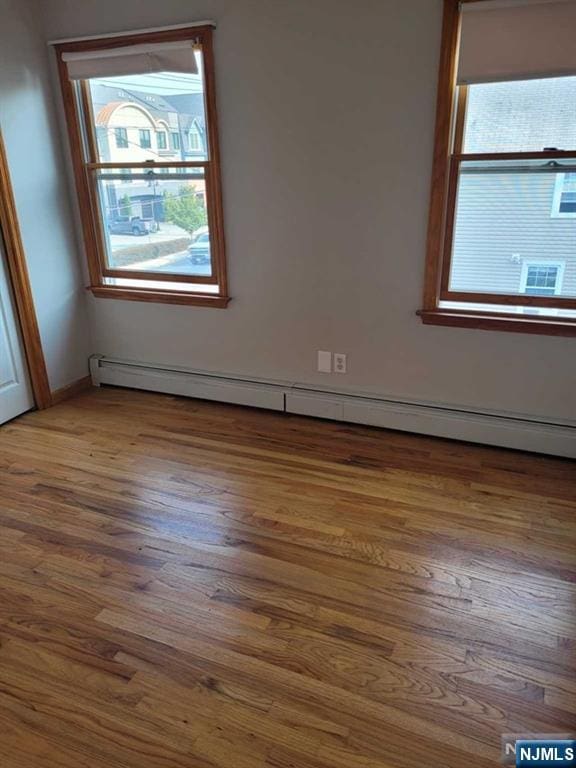 empty room with a baseboard radiator and wood finished floors