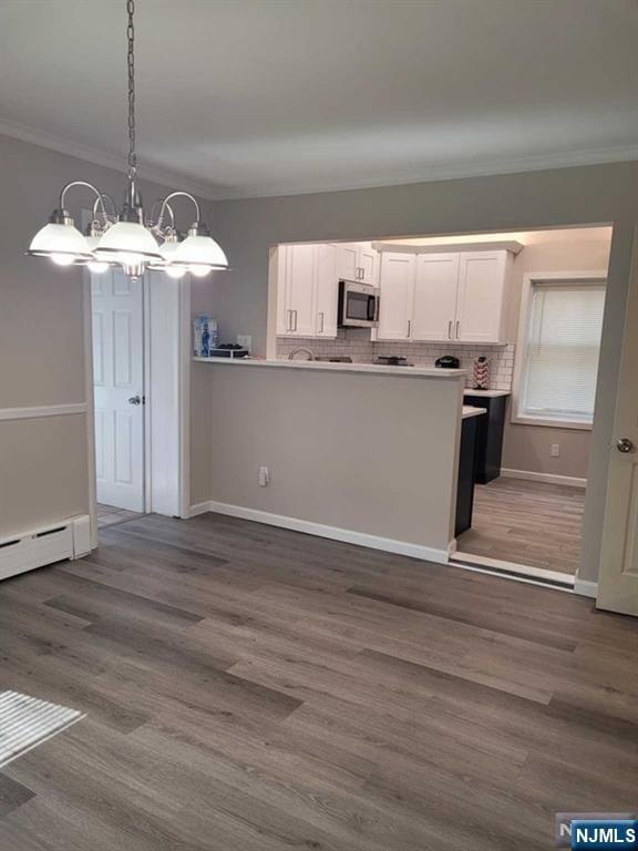 kitchen with dark wood-style floors, white cabinets, stainless steel microwave, and crown molding