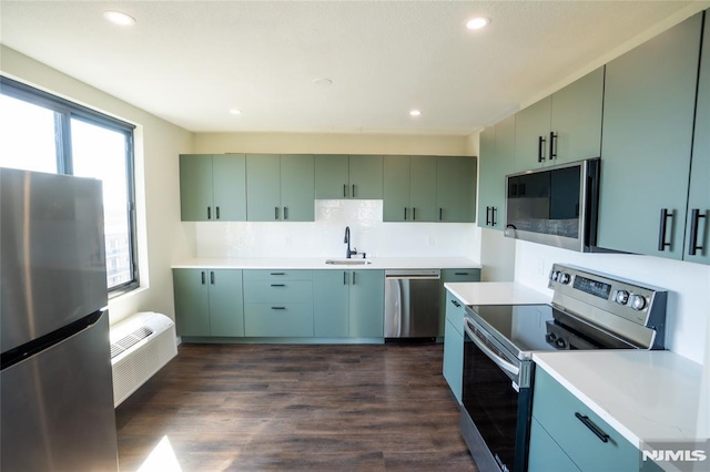 kitchen featuring dark wood finished floors, a sink, light countertops, appliances with stainless steel finishes, and backsplash