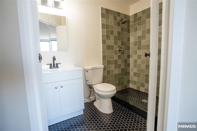 full bathroom featuring tile patterned flooring, toilet, tiled shower, and vanity