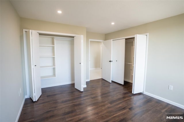 unfurnished bedroom with recessed lighting, baseboards, multiple closets, and dark wood finished floors