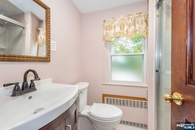 bathroom featuring toilet, radiator heating unit, vanity, and a shower with shower door