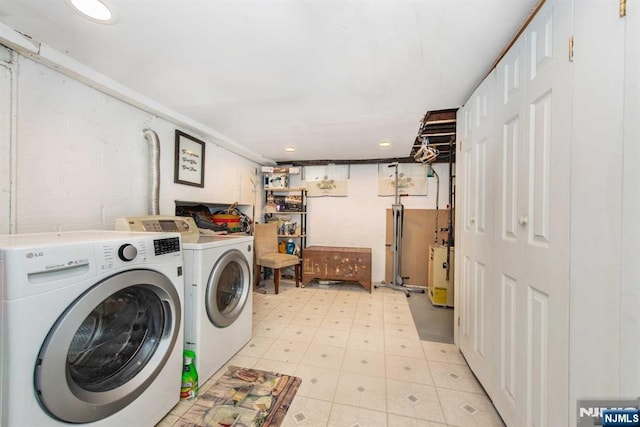 laundry area with concrete block wall, light floors, recessed lighting, washing machine and dryer, and laundry area