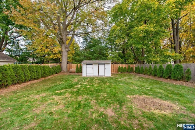 view of yard with a shed, a fenced backyard, and an outbuilding