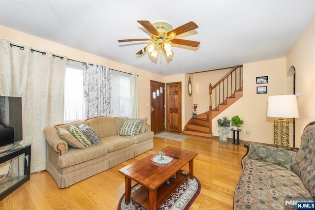 living area featuring stairs, wood finished floors, and a ceiling fan