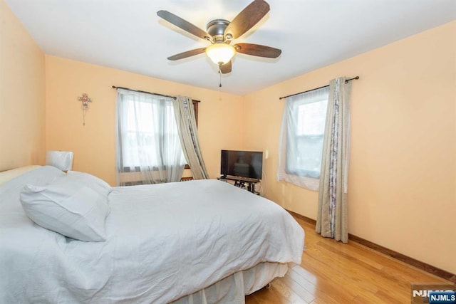 bedroom featuring baseboards, a ceiling fan, and light wood-style floors