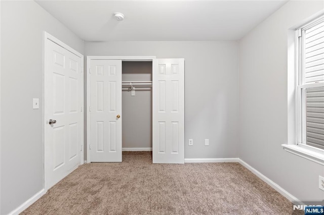 unfurnished bedroom with carpet floors, a closet, and baseboards