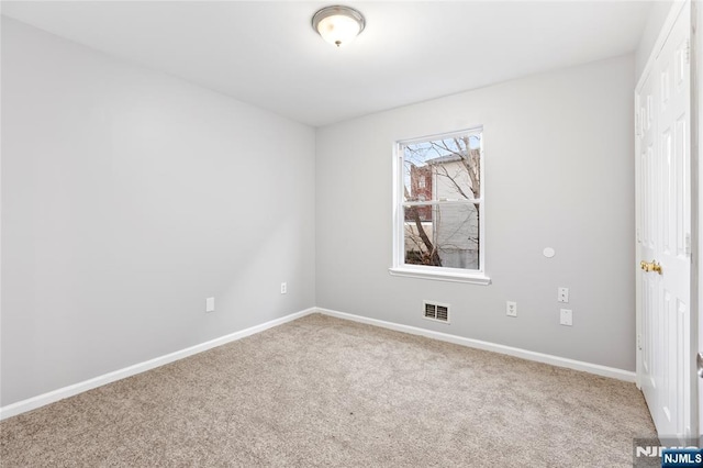 spare room featuring carpet floors, visible vents, and baseboards