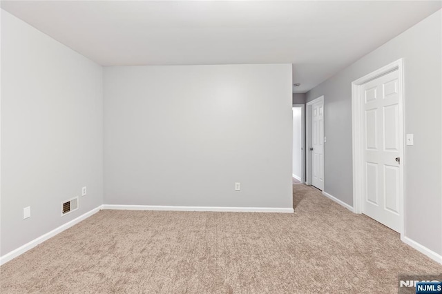 unfurnished room featuring carpet floors, visible vents, and baseboards