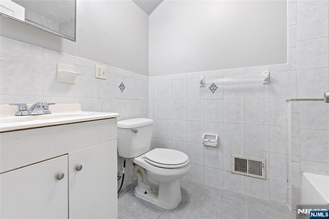 bathroom featuring visible vents, toilet, tile patterned flooring, vanity, and tile walls