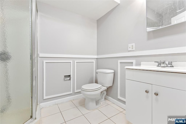 bathroom with toilet, a shower stall, vanity, and tile patterned floors