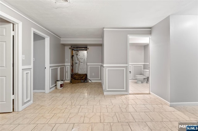 spare room featuring wainscoting, visible vents, and a decorative wall