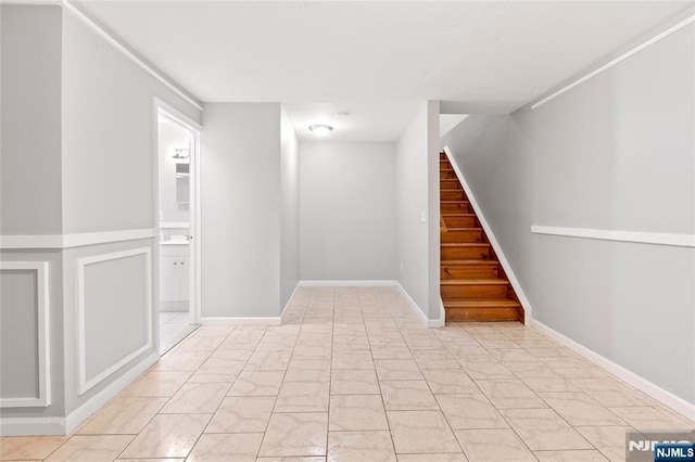 basement with marble finish floor, stairs, and baseboards