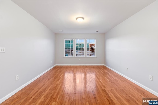 spare room with baseboards, visible vents, and light wood-style floors