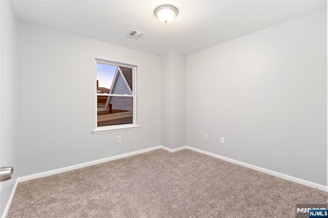 carpeted spare room featuring visible vents and baseboards