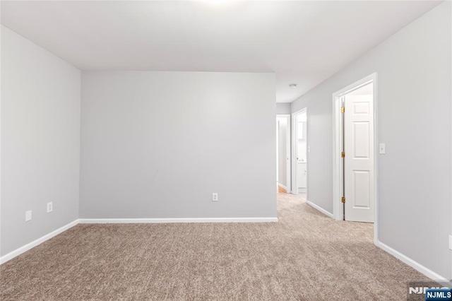 unfurnished room with baseboards and light colored carpet