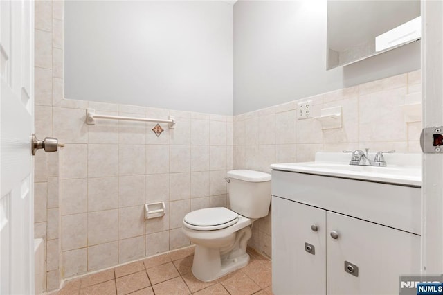 bathroom with toilet, tile patterned flooring, tile walls, and vanity