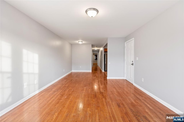 spare room with baseboards and light wood finished floors