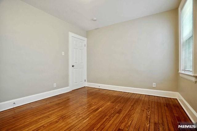 unfurnished room with baseboards and hardwood / wood-style flooring