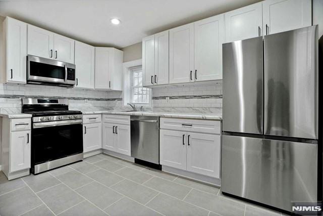 kitchen featuring tasteful backsplash, white cabinetry, and stainless steel appliances