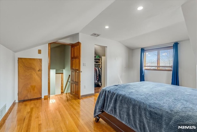 bedroom with visible vents, lofted ceiling, recessed lighting, light wood-style floors, and a walk in closet