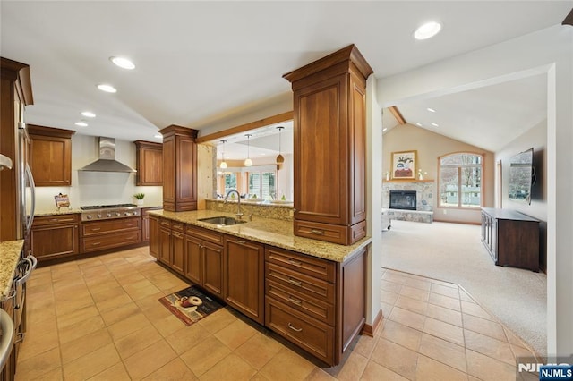 kitchen featuring stainless steel gas cooktop, light colored carpet, vaulted ceiling, a sink, and wall chimney exhaust hood