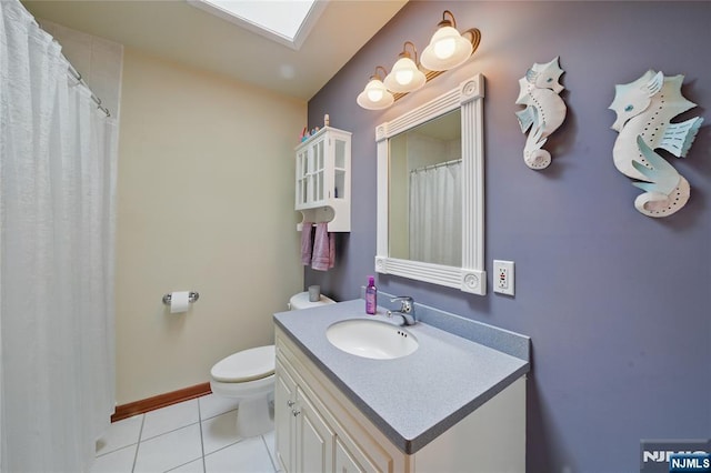 full bathroom featuring a skylight, toilet, vanity, tile patterned flooring, and baseboards