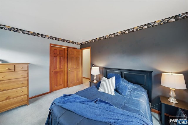 bedroom with baseboards, a closet, and light colored carpet