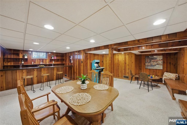 dining room with carpet floors, bar area, and wood walls