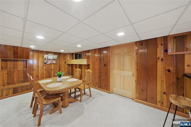 carpeted dining area with recessed lighting and wooden walls