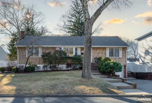 ranch-style house with a lawn, driveway, a chimney, and a shingled roof