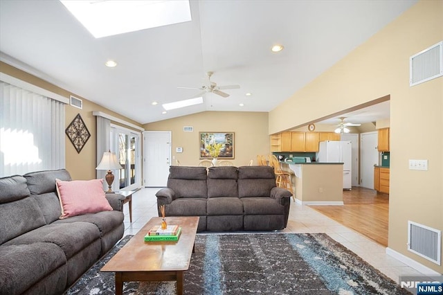 living room with light tile patterned floors, visible vents, and lofted ceiling with skylight