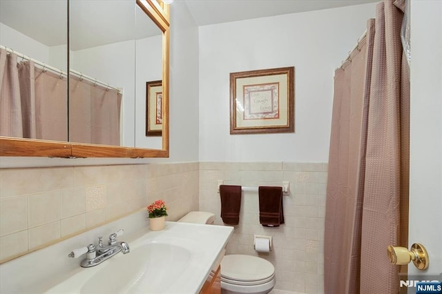 full bath featuring wainscoting, vanity, toilet, and tile walls