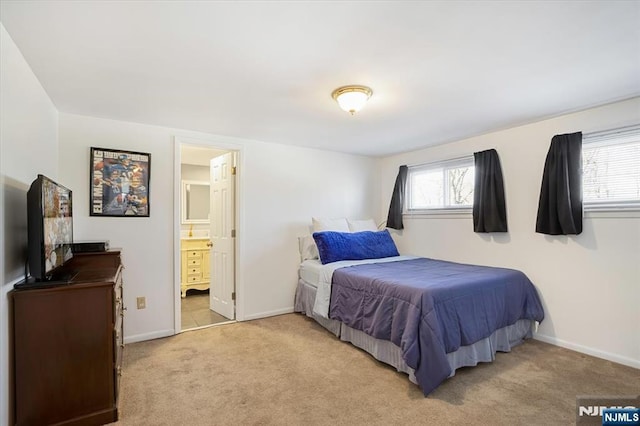 bedroom featuring light carpet, ensuite bath, multiple windows, and baseboards