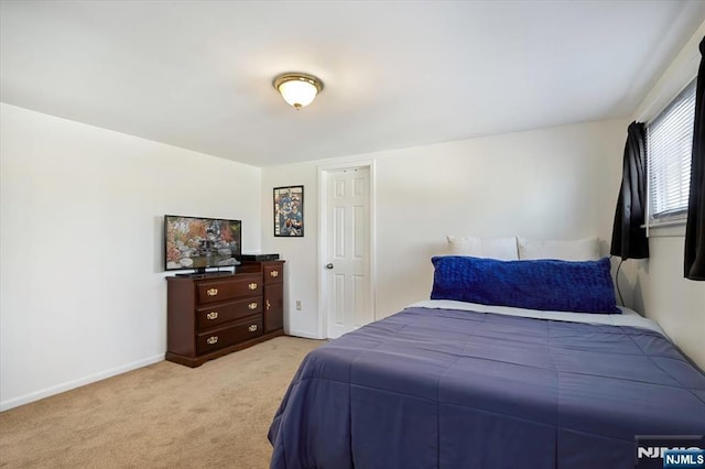 bedroom with light colored carpet and baseboards