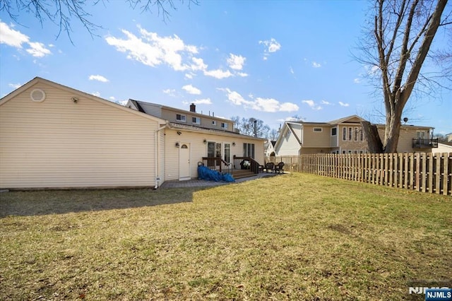 rear view of house featuring fence, a lawn, and a wooden deck