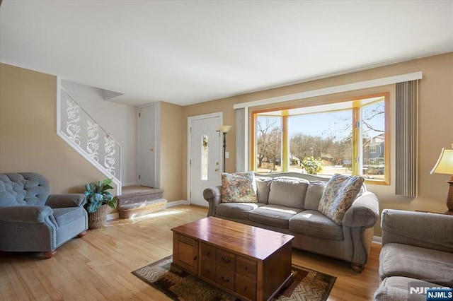 living room with light wood-style flooring, stairway, and baseboards