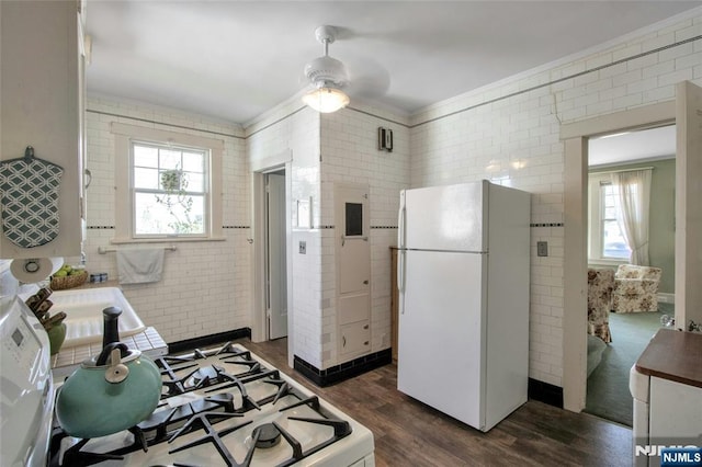 kitchen featuring dark wood-style floors, freestanding refrigerator, ceiling fan, ornamental molding, and gas range